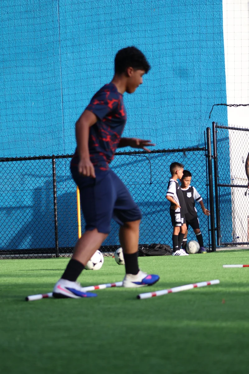 A player in a dark training kit practices on the turf