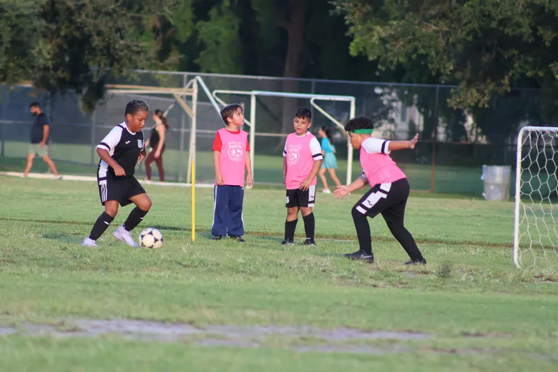 Children in pink bibs defend against a player with the ball