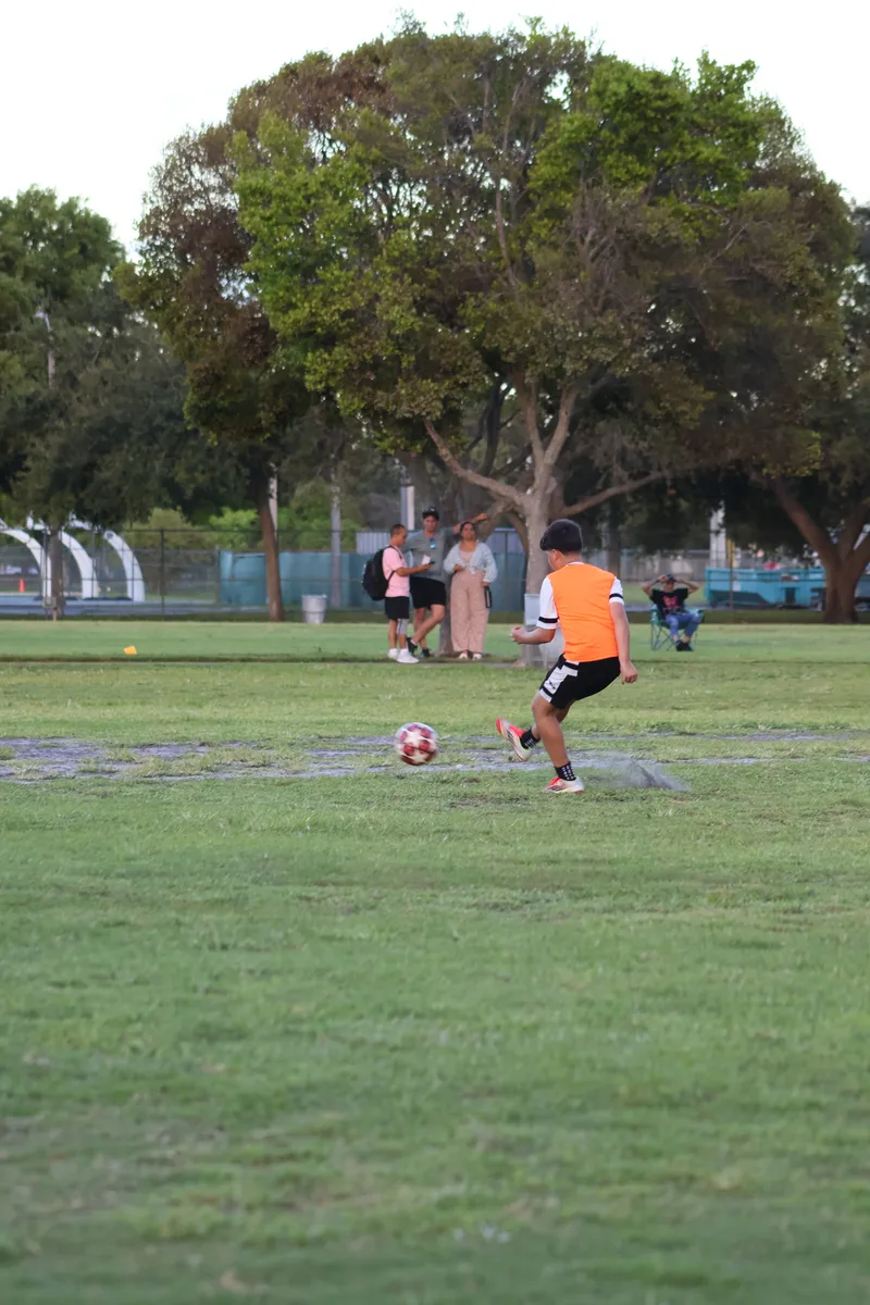 A player in an orange bib trains on the open field