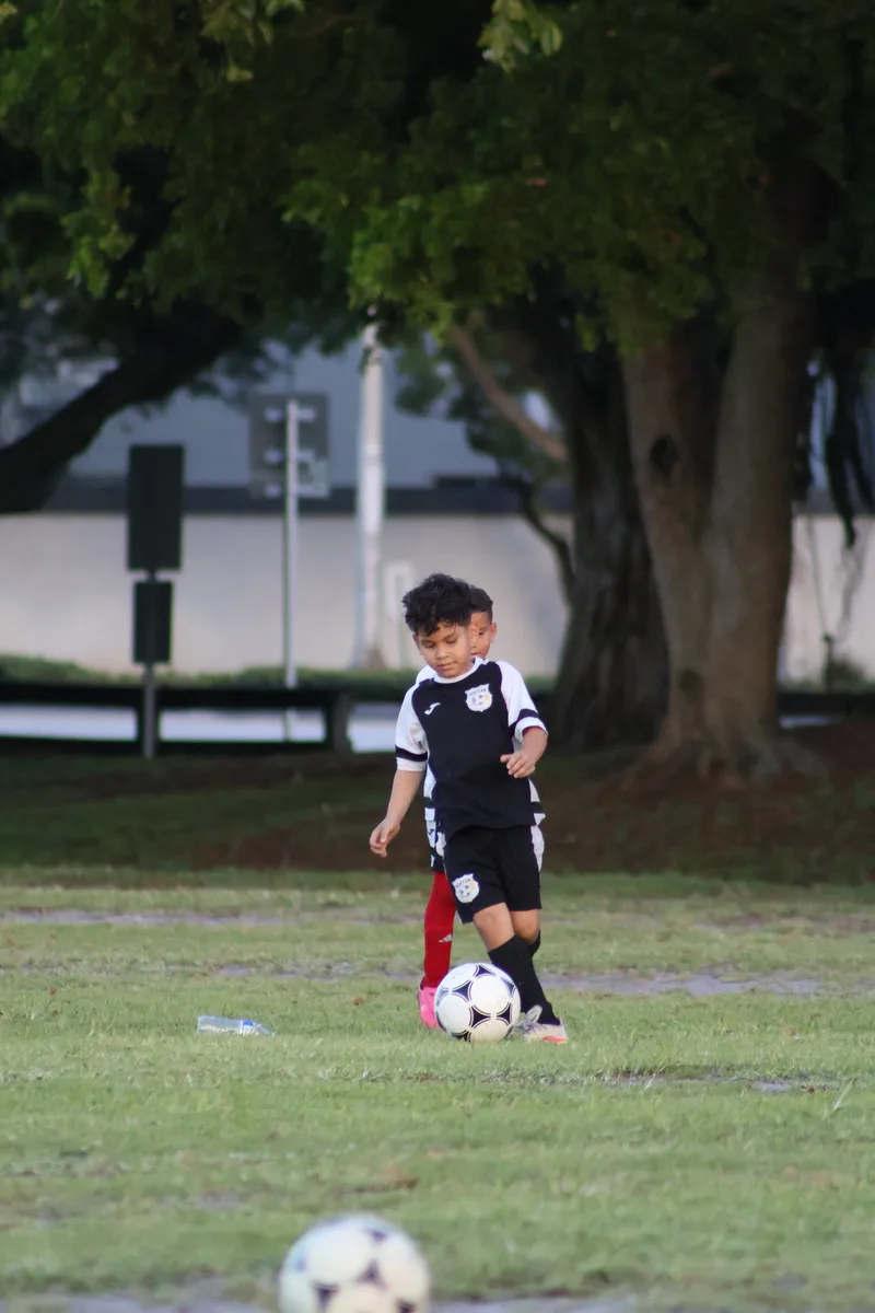A young player approaches the ball in the shade