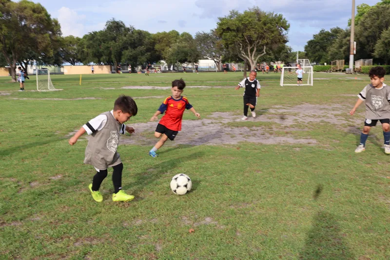 A player in a gray bib and yellow cleats kicks the ball