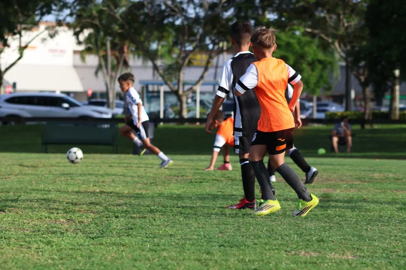 Players in orange bibs move across the field