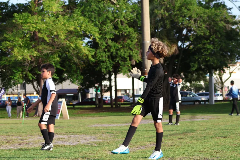 A player wearing goalkeeper gloves stands on the field