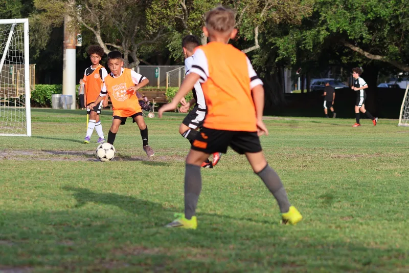 Two players in orange bibs face each other with the ball